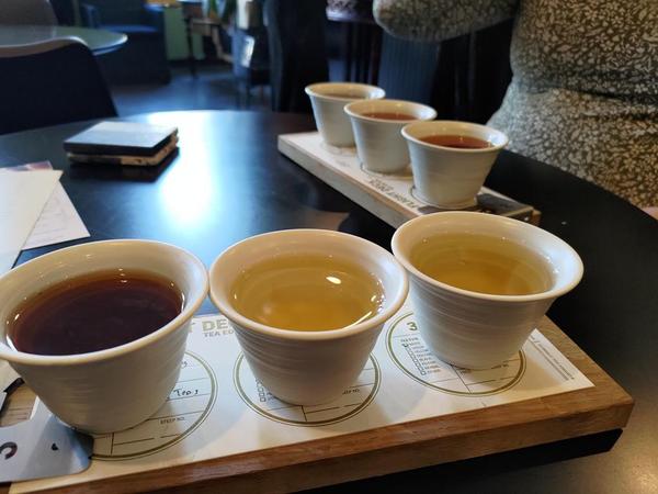 three small, white ceramic tea cups on a woodenboard