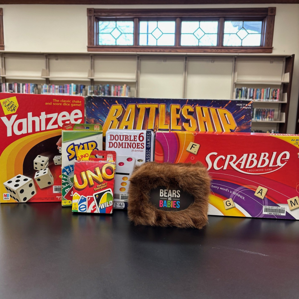 Various games staggered between each other on a table. The board games can be found and checked out from the library.