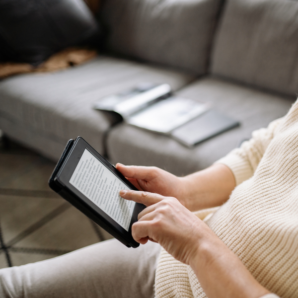 Someone sitting down and reading from their kindle.