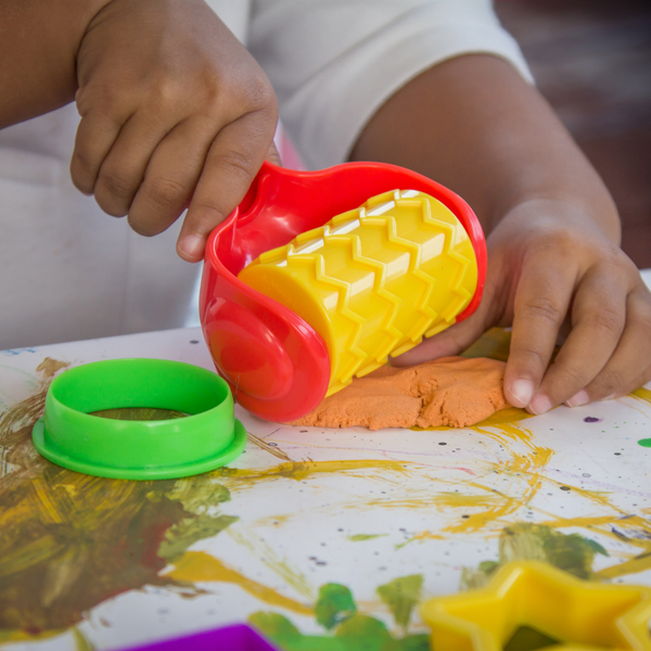 A child rolling out Play-Doh.