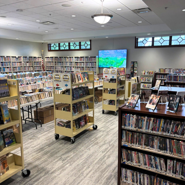 Rows of books and DVDs on shelves, carts, and tables.