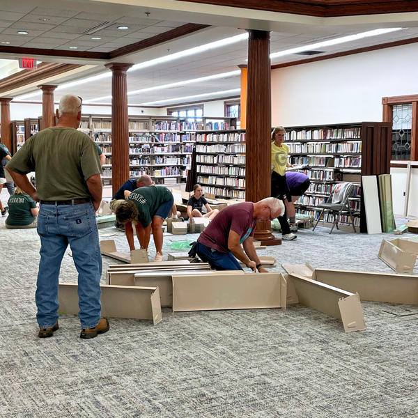 Volunteers assemble library book shelves.