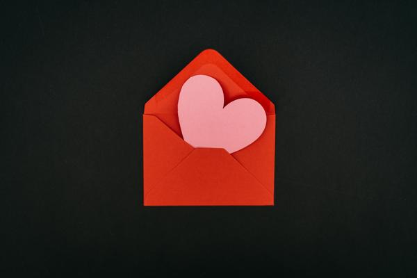 pink paper heart inside a bright red outer envelope set against a black backgroun