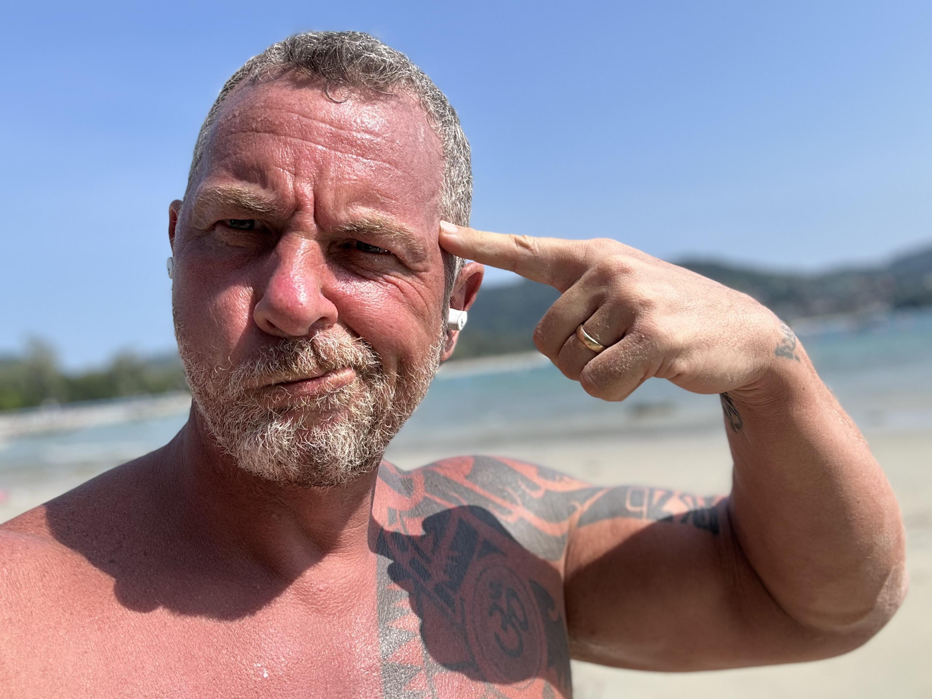 Dax Moy pointing to his temple on the beach