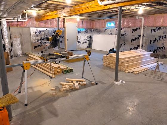 unfinished basement with miter box saw and studs