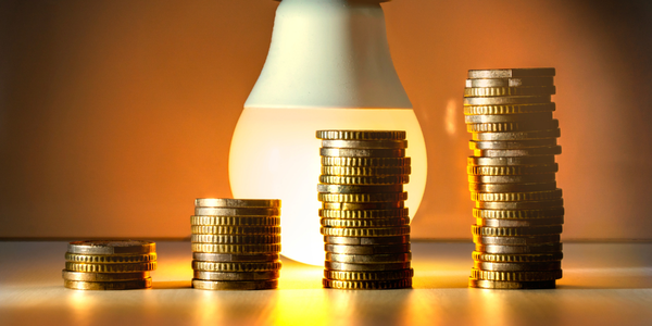 Stacks of coins in front of a light bulb.