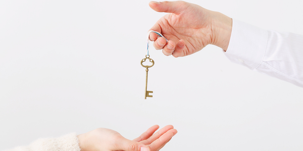 A hand holding a key, amount to give it to another hand.