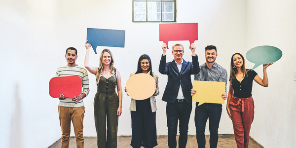 A group of people standing in a line holding up speech bubble type signs.