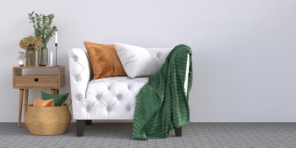 A white sofa, green blanket and personal items