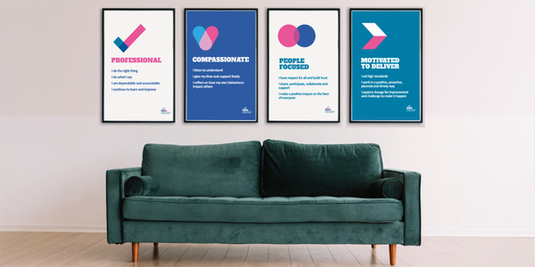 ISHA's values shown as large posters behind a teal sofa.