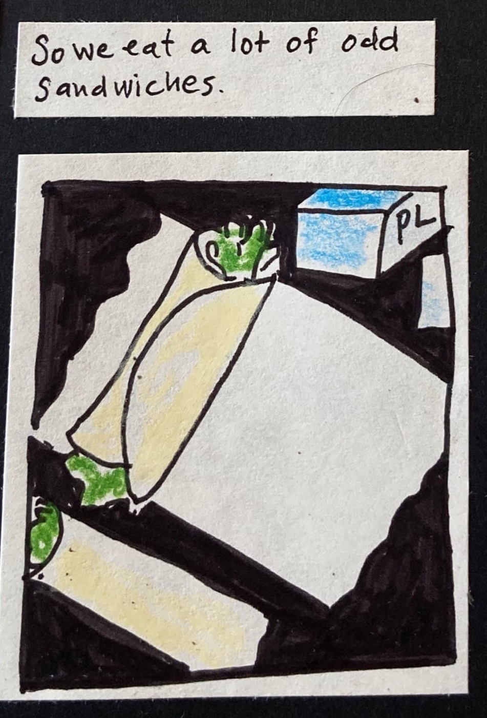 So we eat a lot of odd sandwiches. / (rolled up tortilla with lettuce sticking out both ends, on top of rectangular white parchment paper.