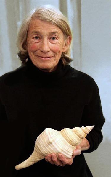 Portrait of a woman in a black sweater holding a very large seashell.