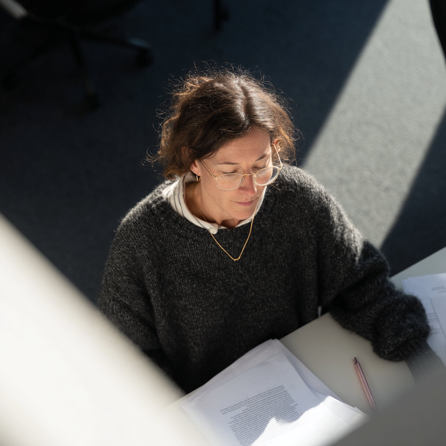 A bookkeeping professional reviewing invoices and receivable statements at a sunlit desk
