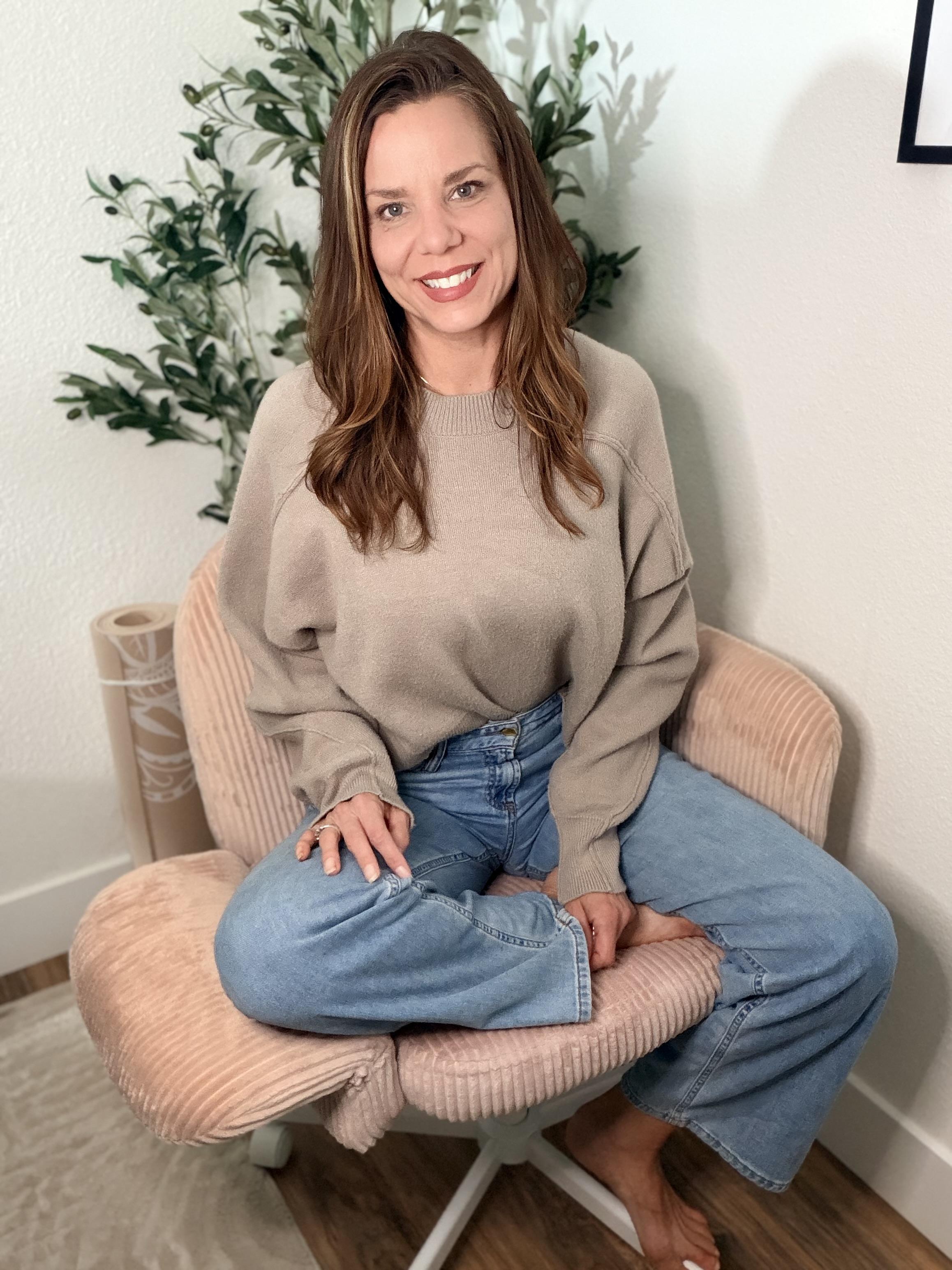 Kelly, certified health and wellness coach, smiling in a cozy sweater