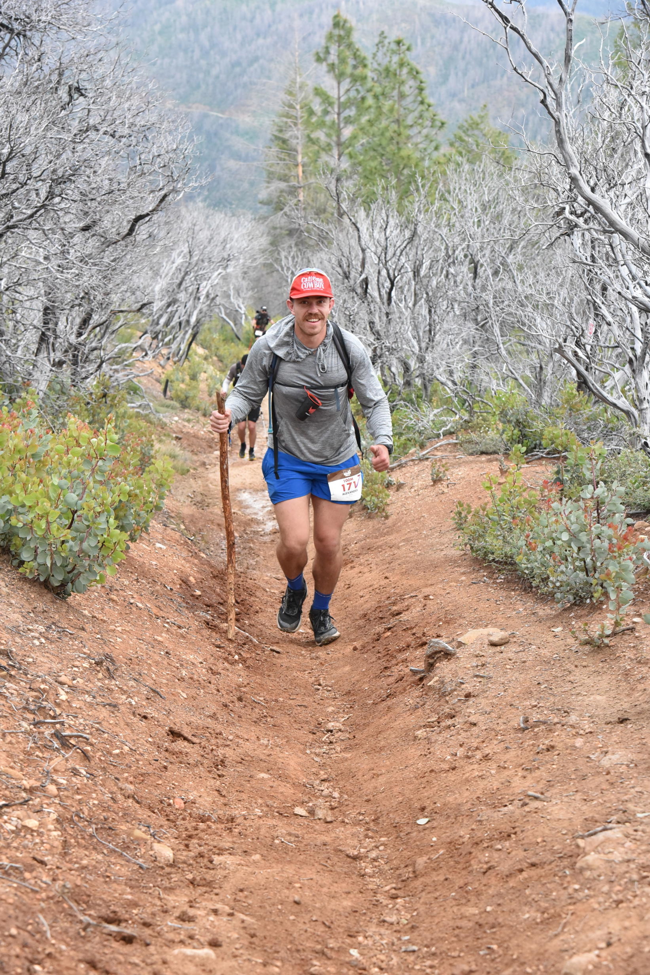 Alex Rojas smiling while climbing a mountain trail during an ultramarathon