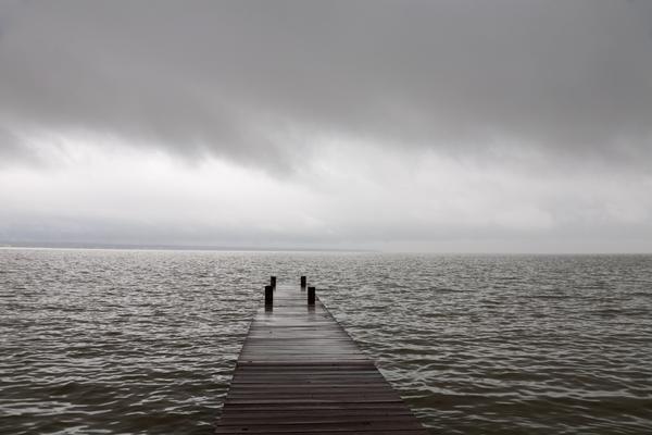 "Dock to the Unknown" A wooden dock floats over the water, leading to a gray and cloudy storm