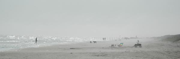 A striped beach chair shines through the fog, as true beach lovers enjoy the mystery
and beauty.