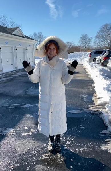 Heidi Straube photographer plays in snow with long white down coat and fluffy fur trimmed hood Old Saybrook Connecticut winter 2022
