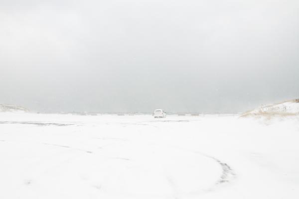 A white truck with red tail lights is parked in the middle of a blizzard gazing at the ocean Cape Cod Massachusetts