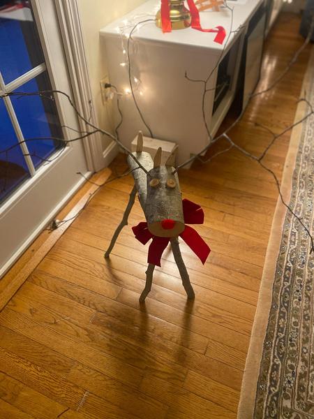 A reindeer made of birch log and twigs sports a bright red nose, snappy red tie, and invites you to the tiny light glow of hope