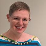 Photo of Rebeka Darylin, who is white with very short brown hair and glasses.