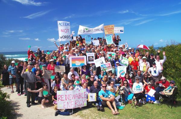 A crowd of people holding protest signs next to the beach