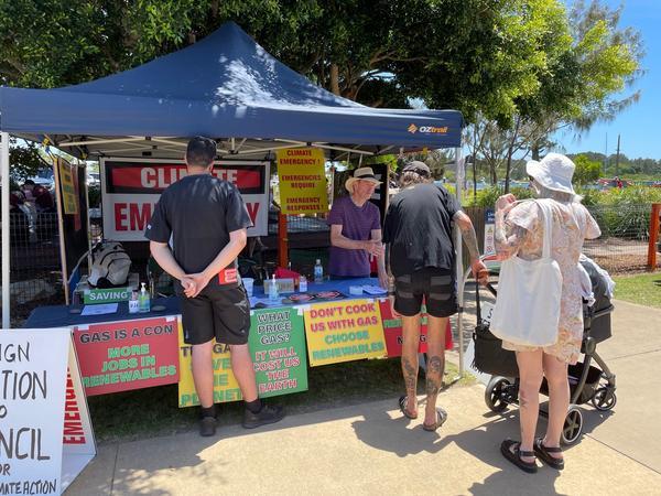 People queue at a market stall on a sunny day