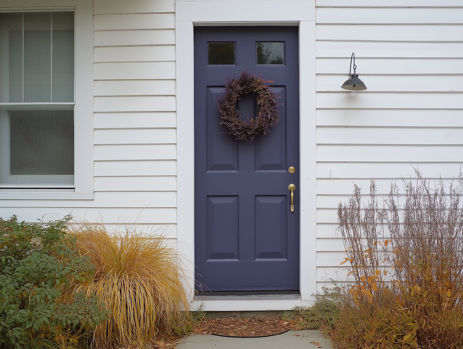 Welcoming front door of a white home with a wreath and lantern