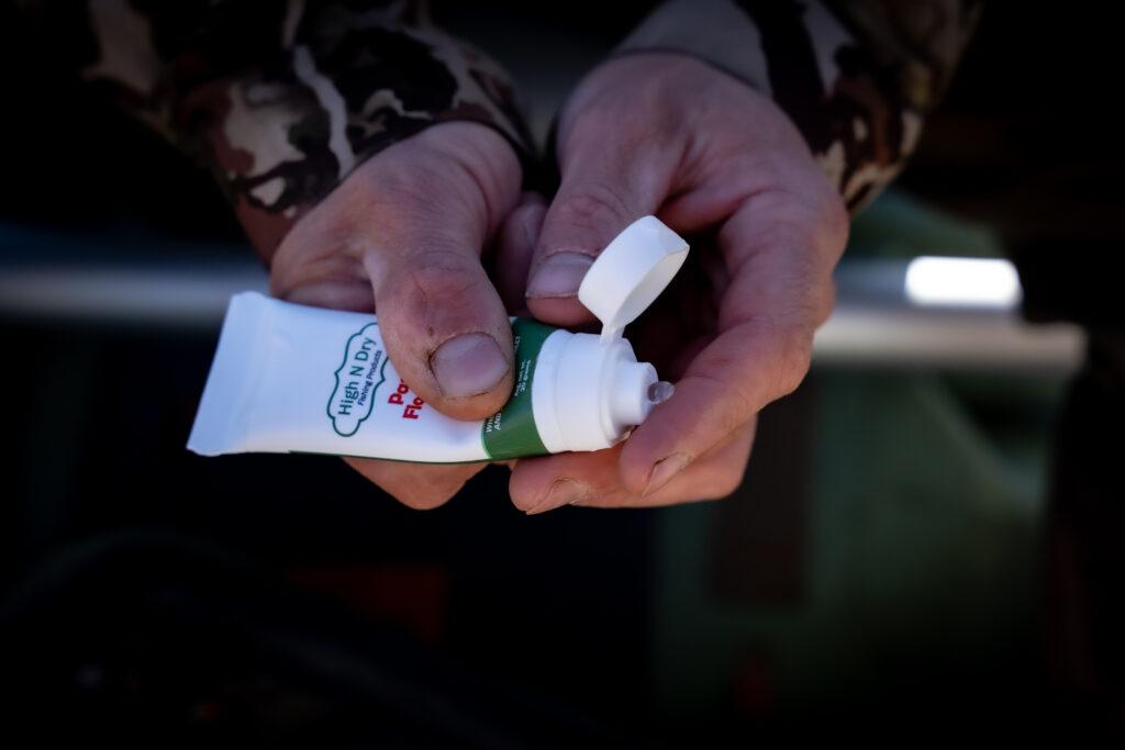A close-up of a hand holding a tube of cream
            
            Description automatically generated