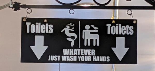 Bathroom sign with arrows to toilets with a mermaid and a centaur, then reads whatever just wash your hands