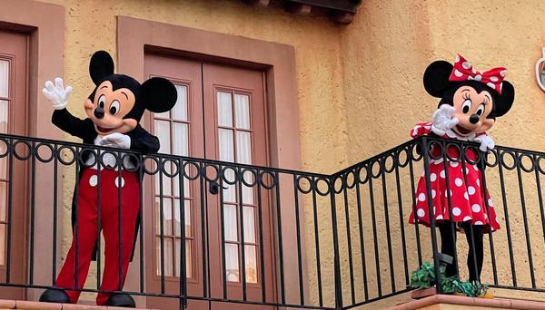 Mickey and Minnie Mouse on a balcony waving 