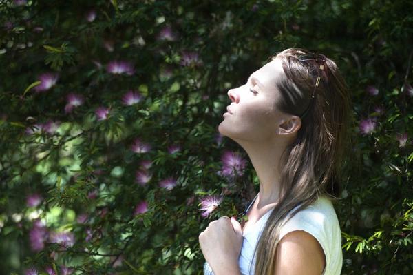 Act happy week day 5 women is basking in the fresh air and sun with beautiful bushes around her.