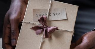 Gift box with a bow and a note that says thank you on it