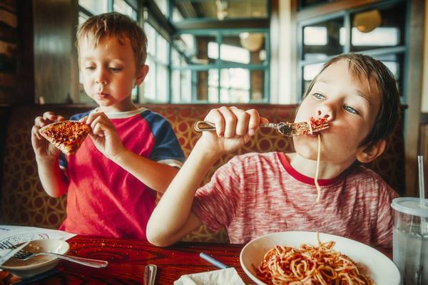 Kids eating spaghetti and pizza