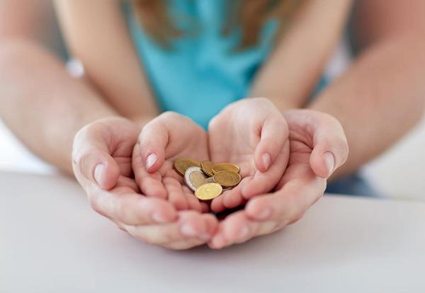 An adult and child's hands holding money