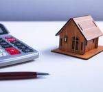 A model wooden house, calculator and a pen