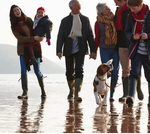 A family walking their dog on the beach