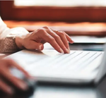 Hands typing on a laptop
