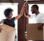 Two people carrying boxes high five each other