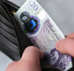 A hand pulling a £20 note from a wallet