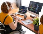 A woman in a wheelchair with a headset and computer