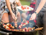 People reaching for kebabs on a bbq