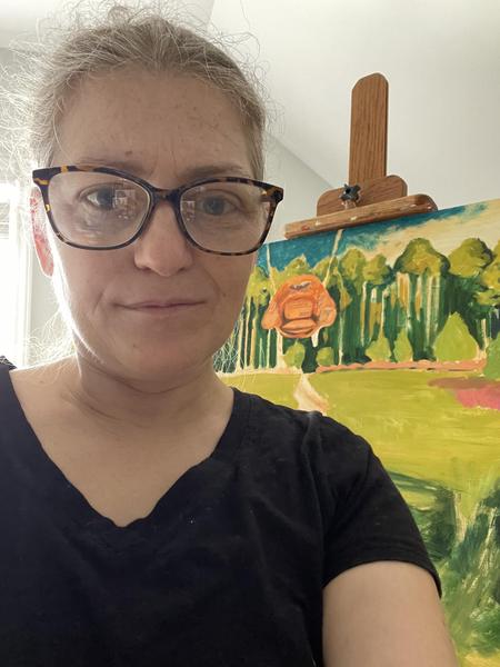 Jennie standing in front of her landscape painting featuring hanging womb chairs.