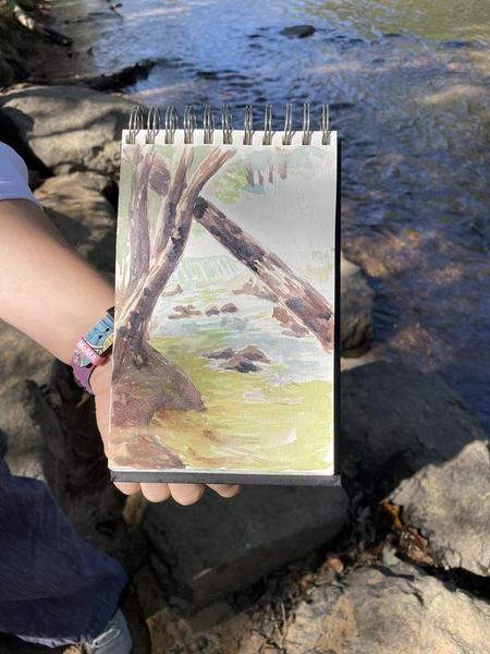 Student painting of the dam through the trees