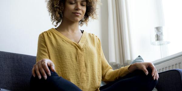 young-woman-sitting-on-couch-at-home-meditating-royalty-free-image-916896348-1530892624.jpg
