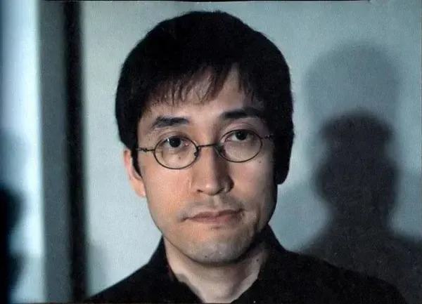Portrait of manga artist Junji Ito wearing round glasses and a dark shirt