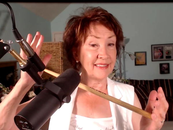 Judy Rodman holding drumstick while singing at a recording mic