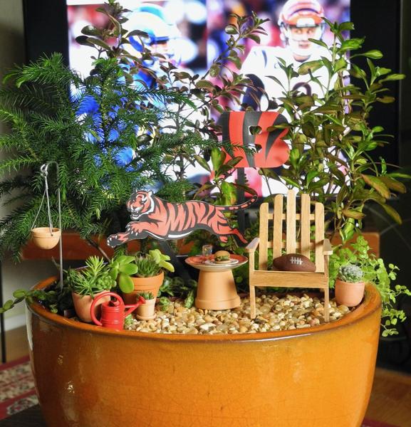 An inground miniature garden with white wicker furniture