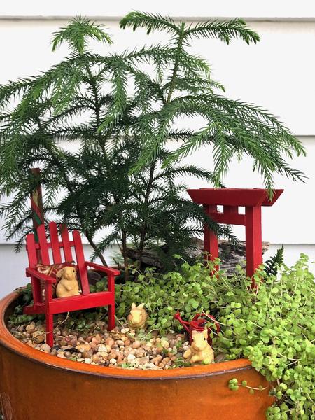 An inground miniature garden with white wicker furniture