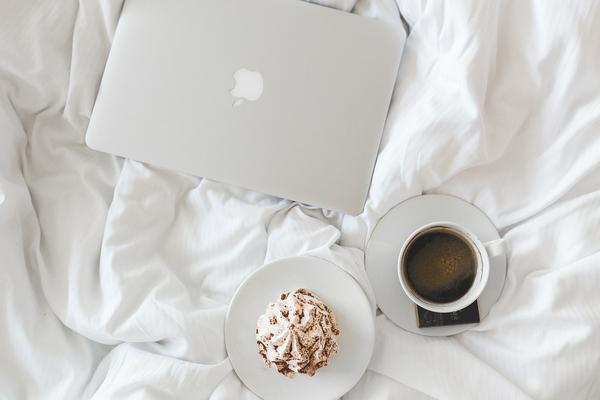 Laptop and coffee on white bed